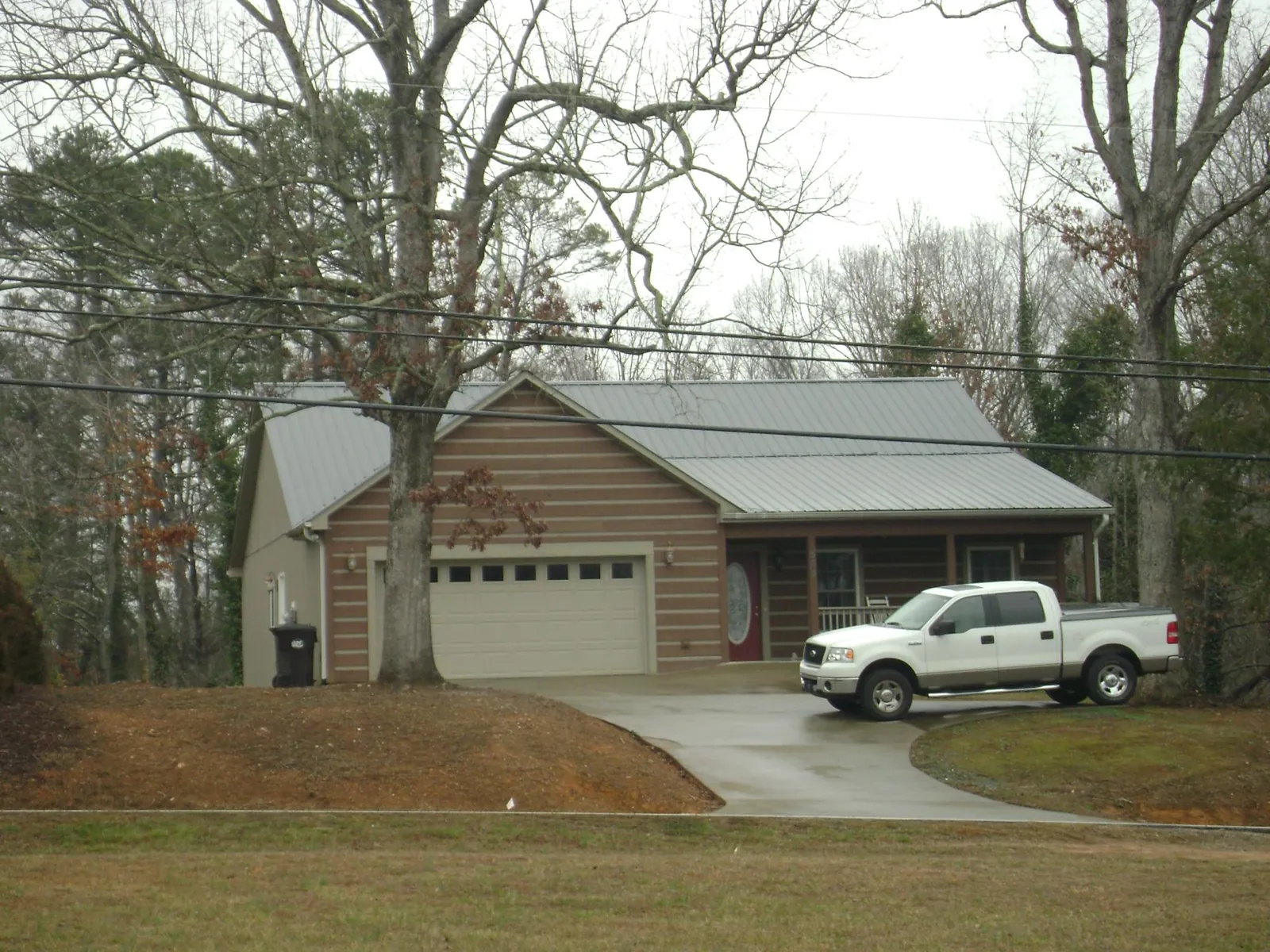 Gray metal roof on a log sided house with an attached two car garage in Glendale